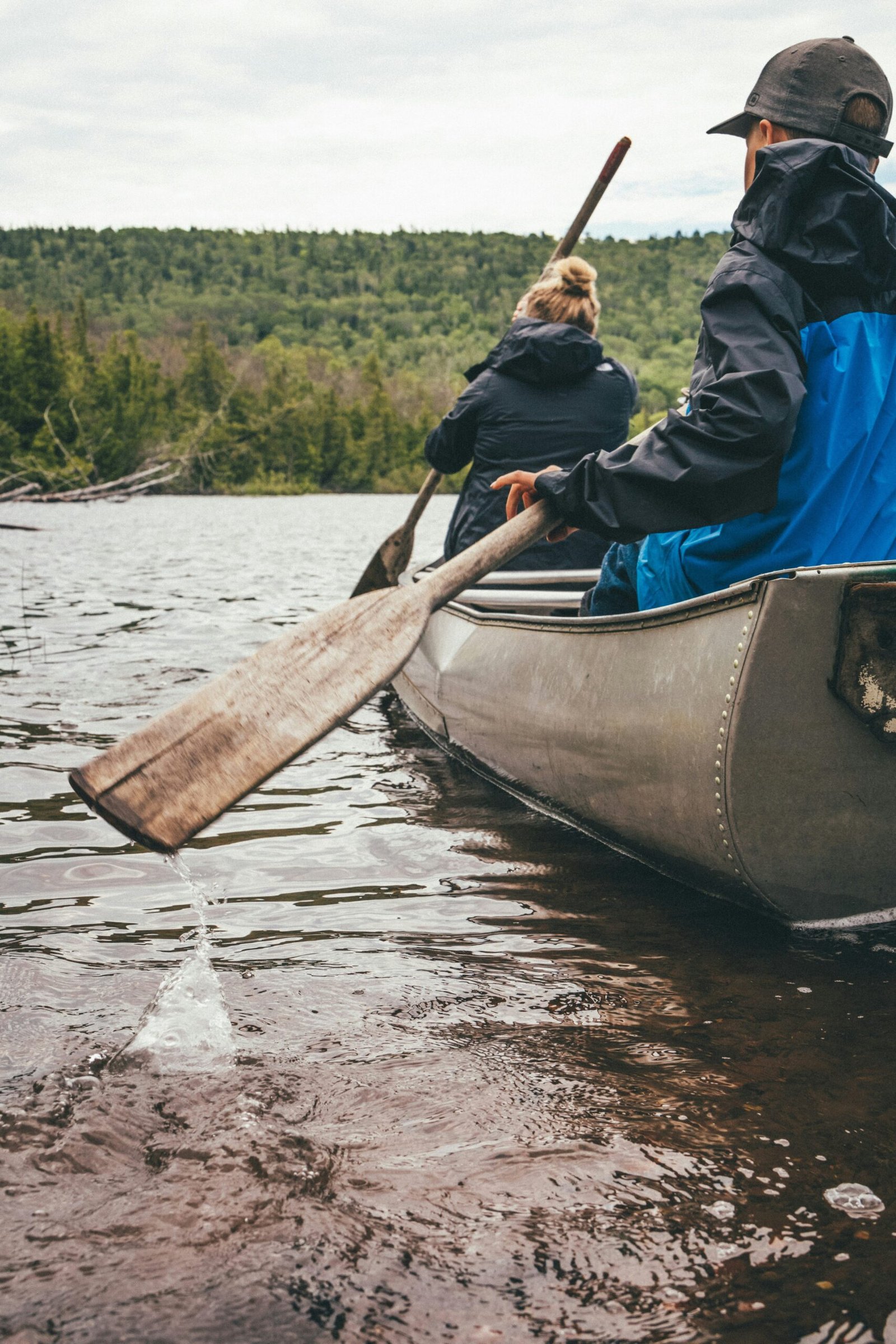 man in blue jacket riding on brown boat during daytime