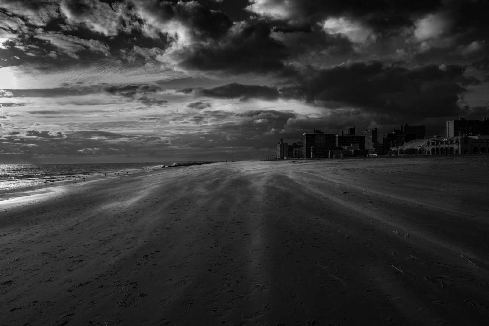 grayscale photo of beach under cloudy sky